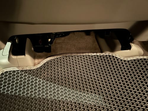 Recenzent pokazuje niedopasowany tylny dywanik samochodowy, który unosi się nad tunelem środkowym.