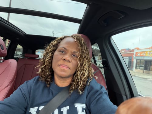 Customer in a car showing their styled, curly mix color blend crochet hair.