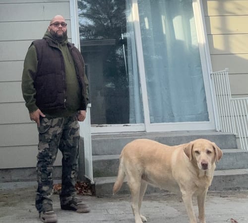 Reviewer standing outside wearing the solid army green ZCL Essential Parker Hoodie under a dark vest.
