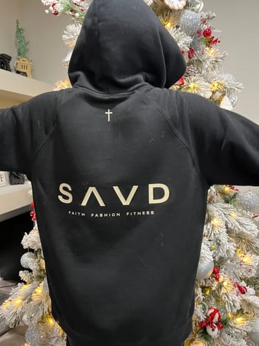Close-up of a customer wearing the back of the black Youth Oversized Hoodie, showing the logo and cross detail.