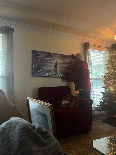 Customer hanging the new Walking on Water faith wall art in a living room.