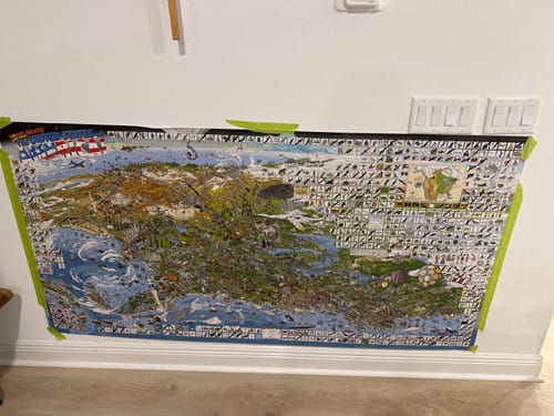 Customer's large World's Greatest Search & Discover poster temporarily taped to a white wall near the floor.