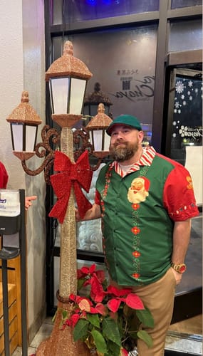Reviewer wearing the green and red Sweet Papa Christmas Button Up shirt at a holiday event.