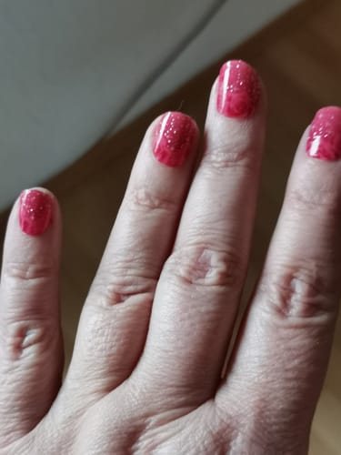 Nahaufnahme der Hand einer Kundin, die die glitzernden rosafarbenen UV-Gel-Nagelfolien 'Glitter Rose Ombré' trägt.
