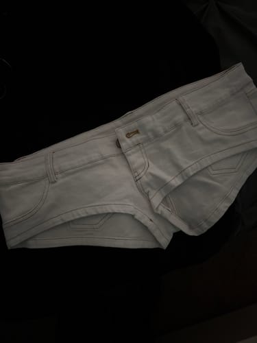 Customer's white denim Micro Mini Shorts laid out flat on a dark surface.
