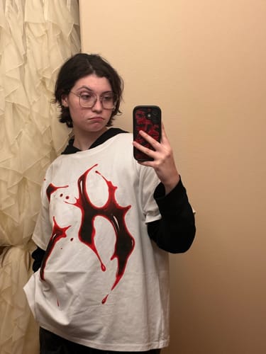 Reviewer wearing an oversized white BACK TO SKULL SHIRT layered over a black long-sleeved shirt for a boxy fit.