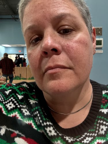 Close-up of a reviewer wearing the thin Chelsea Herringbone Necklace with a patterned sweater.