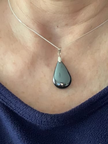 Client(e) portant le pendentif hématite en forme de goutte sur une chaîne.