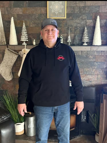 Reviewer standing indoors wearing the black Motion Raceworks Essential Hoodie, showing its fit and length.