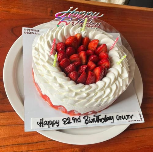 Reviewer's Strawberry Frasier Cake with a 'Happy Birthday' topper, candles, and fresh strawberries for a celebration.