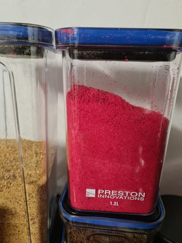 Een transparante Preston Bait Safe-container van een klant, gevuld met felrood aas.