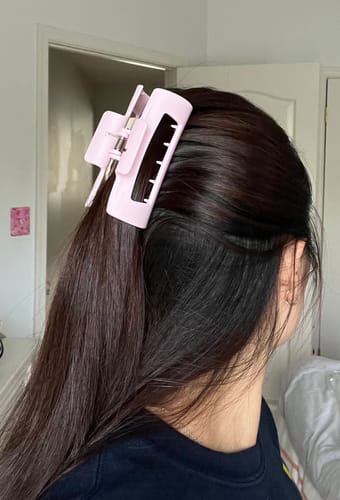 A reviewer shows the light pink cloud clip holding their thick hair securely.