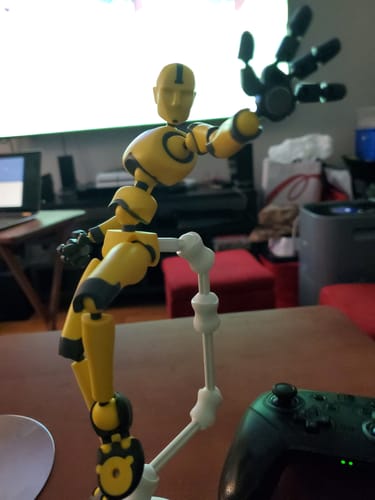 Customer's yellow and black Solar Flare Stickybones figure in a dynamic pose, reaching toward the camera on a wooden table.