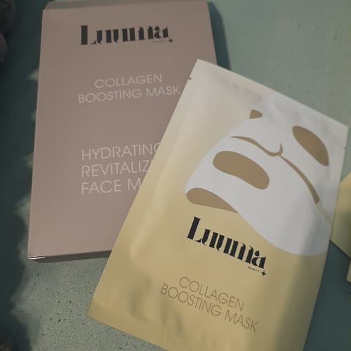 Ein Kunde zeigt die rosafarbene Schachtel und einen einzelnen Beutel der Kollagen Boosting Maske.
