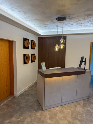 Kunde zeigt vier Holz Wand Deko GENTA an einer Wand in einem modernen Empfangsbereich.