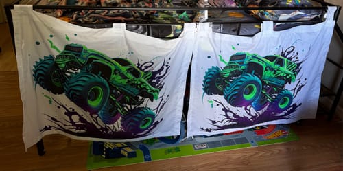 Customer's two Cool Monster Trucks Fabric Panels being used as doors for a child's fort on a bed.