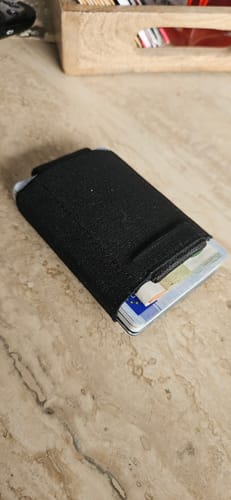 Customer's black Nano Boy card holder wallet filled with cards and resting on a marbled surface.