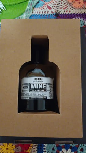 Recensore mostra la boccetta di profumo PIPPI nella sua confezione di cartone.