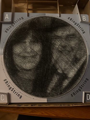 יצירת RingString מוגמרת של לקוחה, המציגה דיוקן פנים שנוצר מחוטים שחורים.