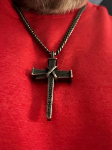Close-up of a reviewer wearing the Nailed to the Cross necklace against a red shirt.