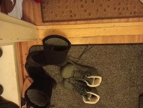 Arvostelijan vihreät Vaistoa Uoma 3 Talvi -kengät eteisen matolla toisten saappaiden vieressä.