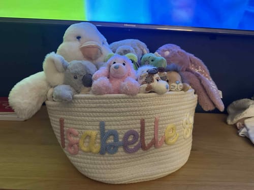 Reviewer's personalized knitted basket with 'Isabelle' in multicolor letters, filled with stuffed animals.
