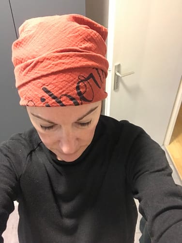 Une cliente porte le Carré Cannelle Liberté noué comme un bandeau sur sa tête, montrant l'inscription « Liberté ».