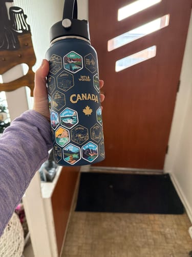 Customer holding their dark blue Canada Bottle with several destination stickers applied.
