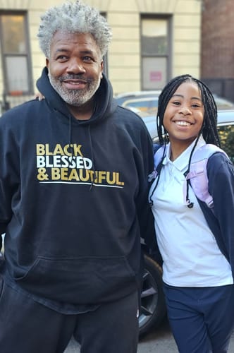 Customer wearing a black hoodie with 'Black Blessed & Beautiful' text, standing with a young person.