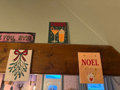 Customer's three finished mini paintings from the Merry Christmas set displayed on a wooden beam.