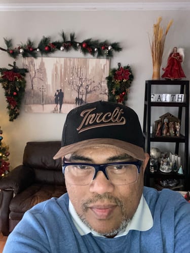 Customer wearing the SCRIPT SNAPBACK hat, showing the black cap, brown suede bill, and front logo.