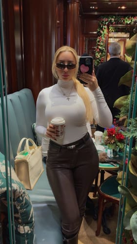 Reviewer in a mirror selfie wearing the white, long-sleeved Butter Turtleneck Contour Bodysuit with dark pants.