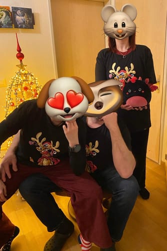 Kundenfoto von drei Personen, die passende schwarze 'Rentier Weihnachten' T-Shirts vor einem Weihnachtsbaum tragen.