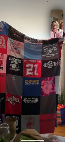 Customer holds up their custom Premium T Shirt Quilt, made of colorful t-shirt squares, while on a video call with two people.