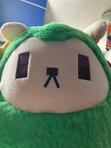 Close-up of a reviewer's Guardian Tales Mayreel Doll, showing the plushie's adorable green and white face.