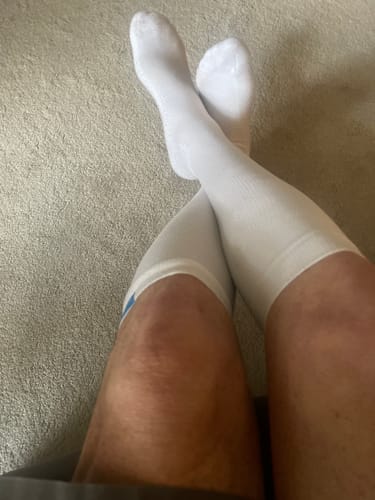 Reviewer wearing a pair of white Performance Eucalyptus Compression Socks with their legs crossed.