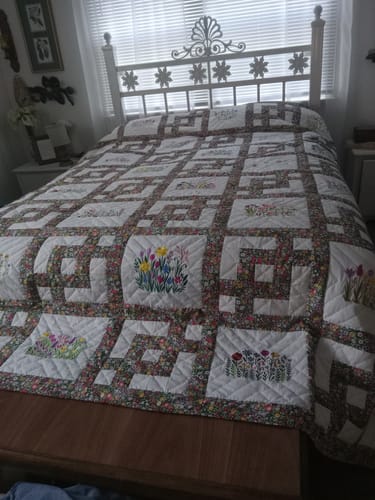 Customer's patchwork quilt on a bed, created with the floral Plentiful Fabric Collection.