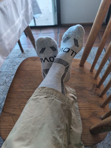 Customer relaxing in a chair, showing the soles of their light grey Women's Alpaca Socks.