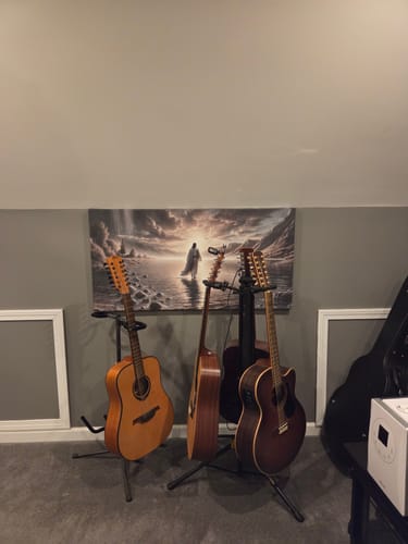 Reviewer's 'Walking on Water - Faith Wall Art II' hanging on a wall above several guitars on stands in a room.