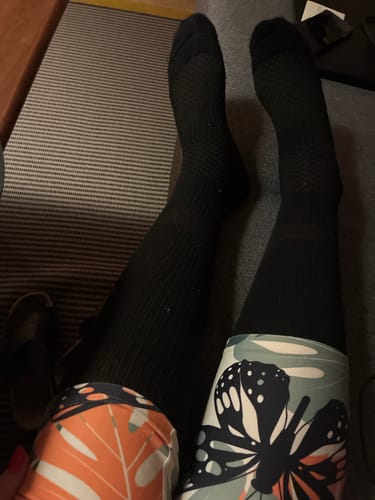 Anmelder slapper af med benene oppe, iført et par sorte støttestrømper.