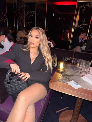 Reviewer sitting in a chic restaurant wearing the black Suiting Mini Skirt.