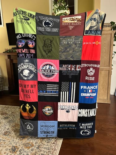 Customer holding up their large Premium T Shirt Quilt, showcasing a colorful variety of t-shirt squares.