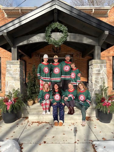 Customer's family of eight posing on their front porch wearing matching green hockey jerseys.