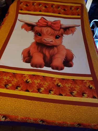 Reviewer's Cute Baby Highland Cows fabric panel sewn into a larger quilt project with orange floral borders.