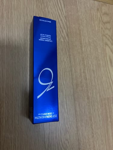 購入者が投稿した、木目調の床の上に置かれたバランサートナーの青い箱。