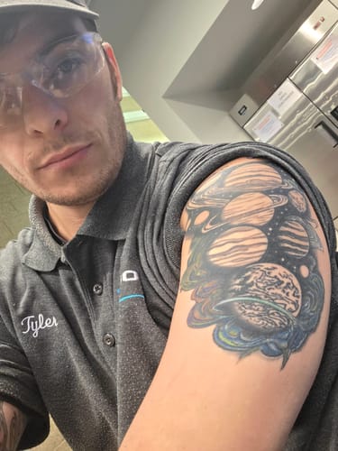 Customer displays their large, intricate solar system tattoo on their arm after using the numbing spray.