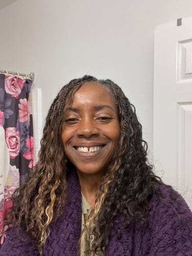 Reviewer smiling, showing off her long boho braids with deep waves using the Burmese Braiding Hair.