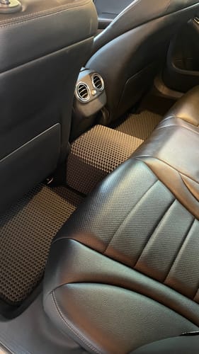 Recenzent pokazuje ciemne, dopasowane dywaniki samochodowe zainstalowane na podłodze tylnych siedzeń.