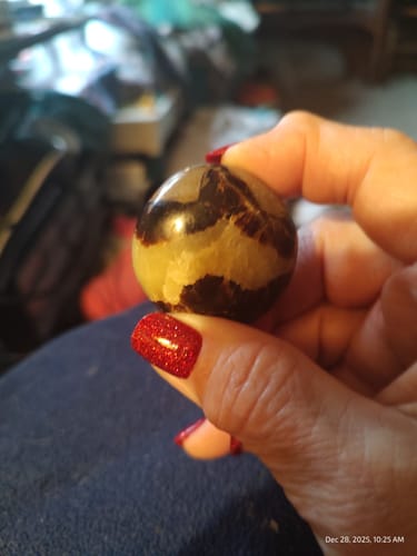 Customer holding a round, polished dragon's blood palm stone in their palm.