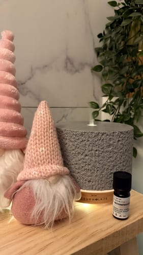 Klantenfoto van de Satori Vulcano Grey diffuser op een houten plank, verlicht naast roze kabouterdecoraties.